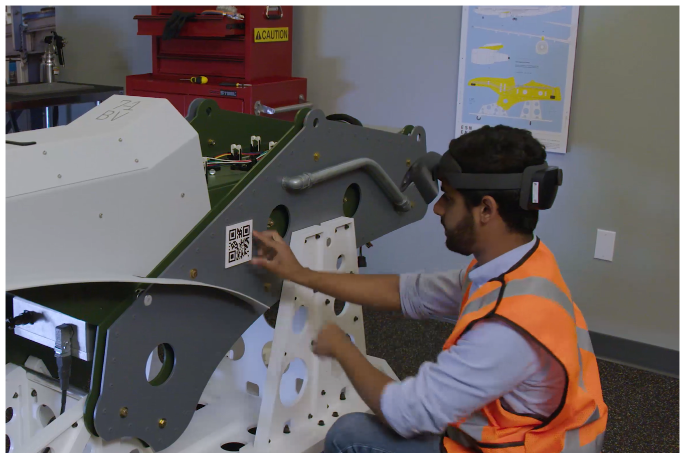 Worker attaching a QR code anchor to machine.