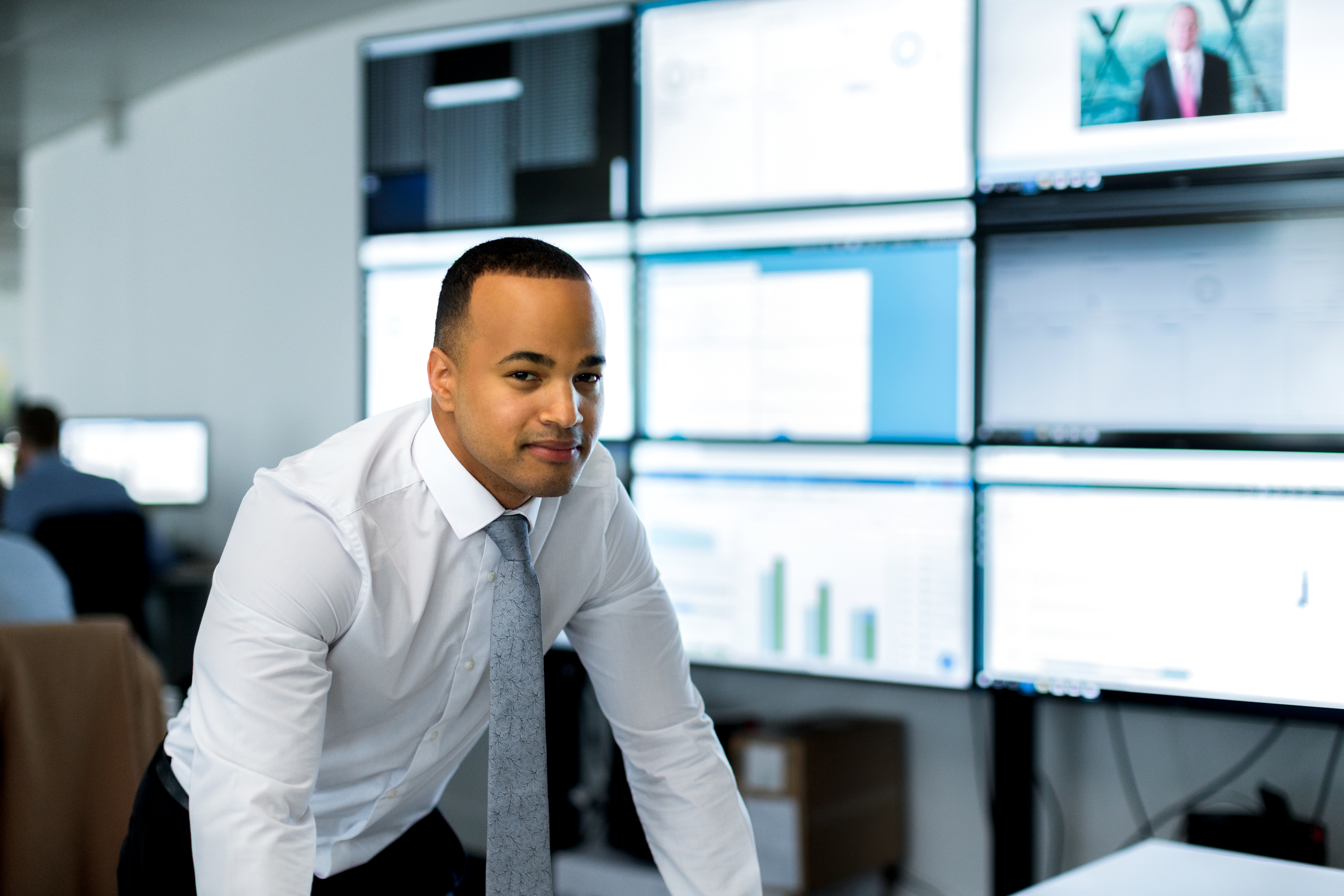 An information worker is pictured in front of a large array of monitors.