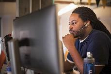 Un uomo che indossa un auricolare e seduto a un computer.