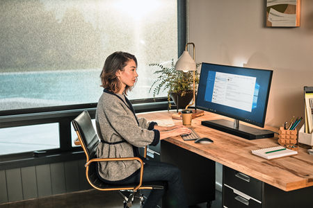 Uma mulher trabalhando em um computador sentada em uma mesa.